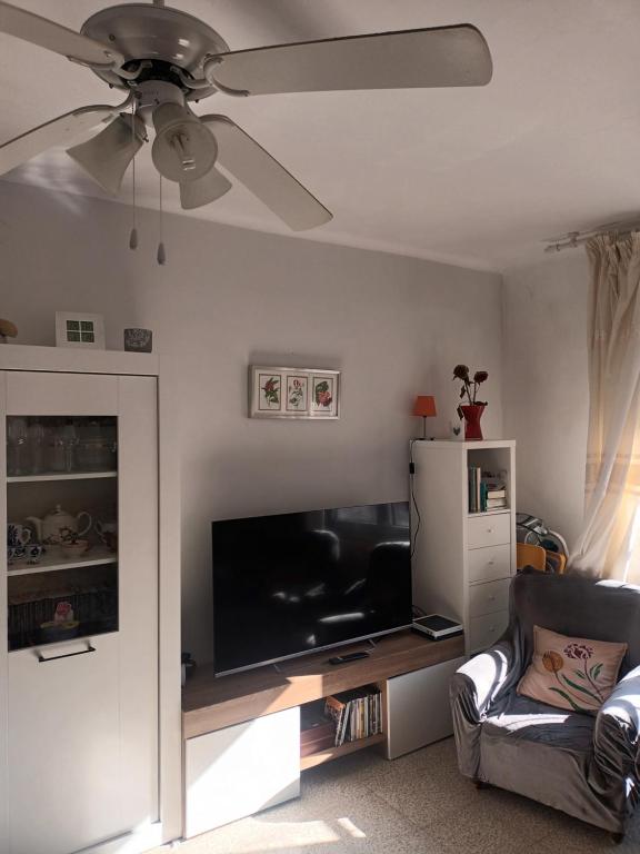 ein Wohnzimmer mit einem Flachbild-TV und einem Deckenventilator in der Unterkunft Habitacion acogedora en Portbou in Portbou