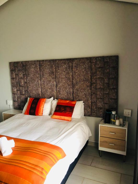 um quarto com uma cama grande e almofadas laranja em Elihle Guest house em Empangeni