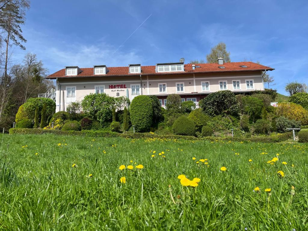 una casa grande con un campo de hierba y flores en Hotel Auf Wolke 8 en Trostberg an der Alz