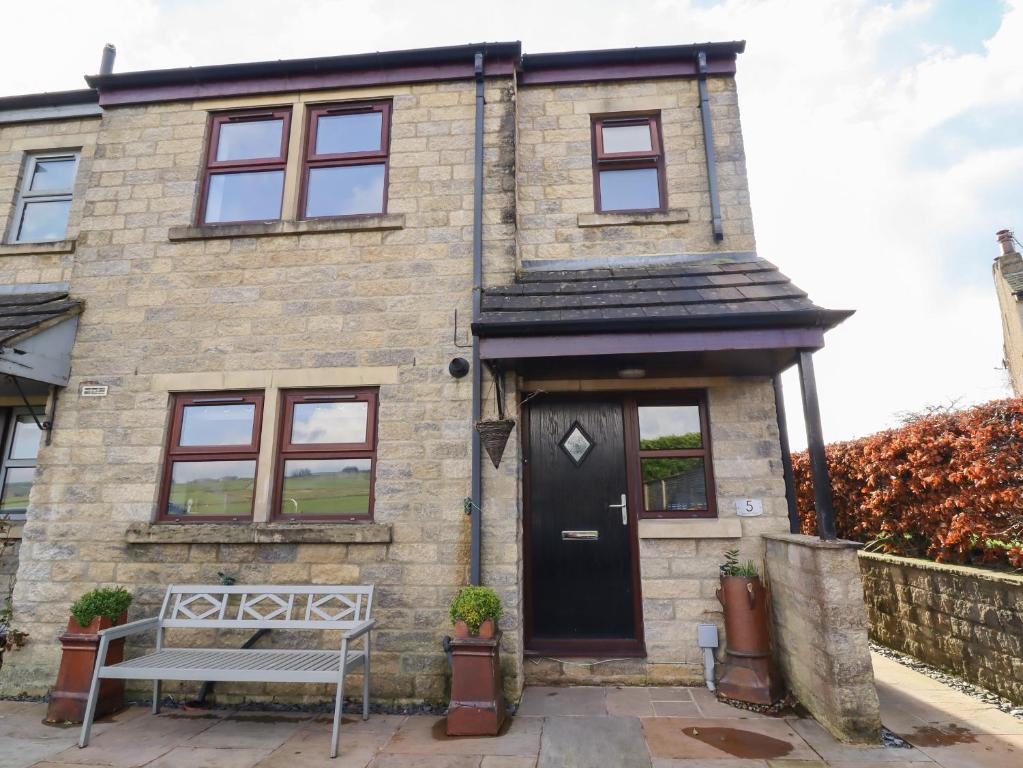 a brick house with a bench in front of it at 5 Emmott Court in Colne