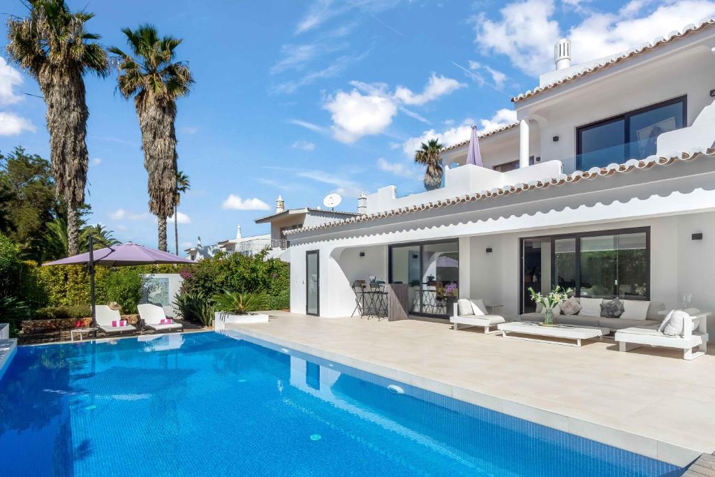a villa with a swimming pool and palm trees at Casa Adélia in Carvoeiro