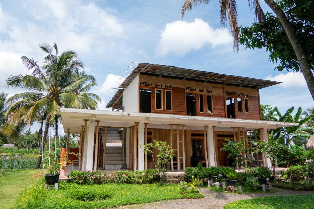 une maison avec des palmiers devant elle dans l'établissement Rinjani Eco Villa, à Bayan