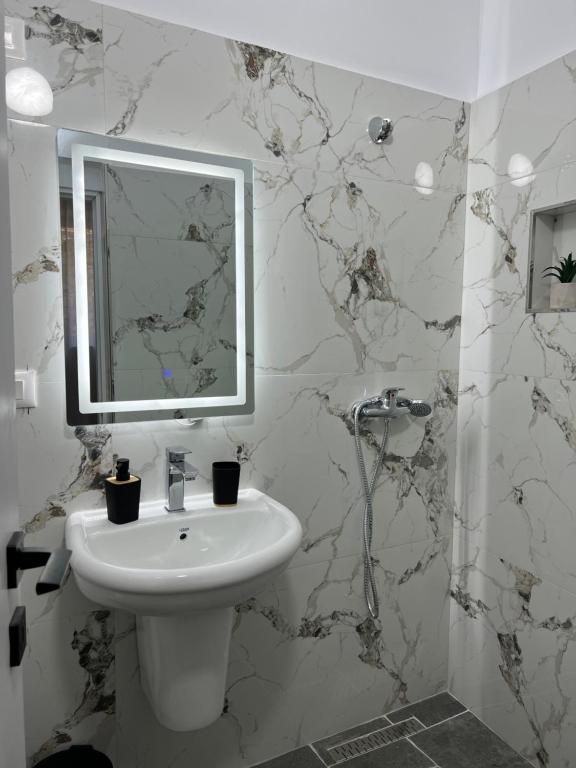 Baño blanco con lavabo y espejo en Nika's Guest House en Berat