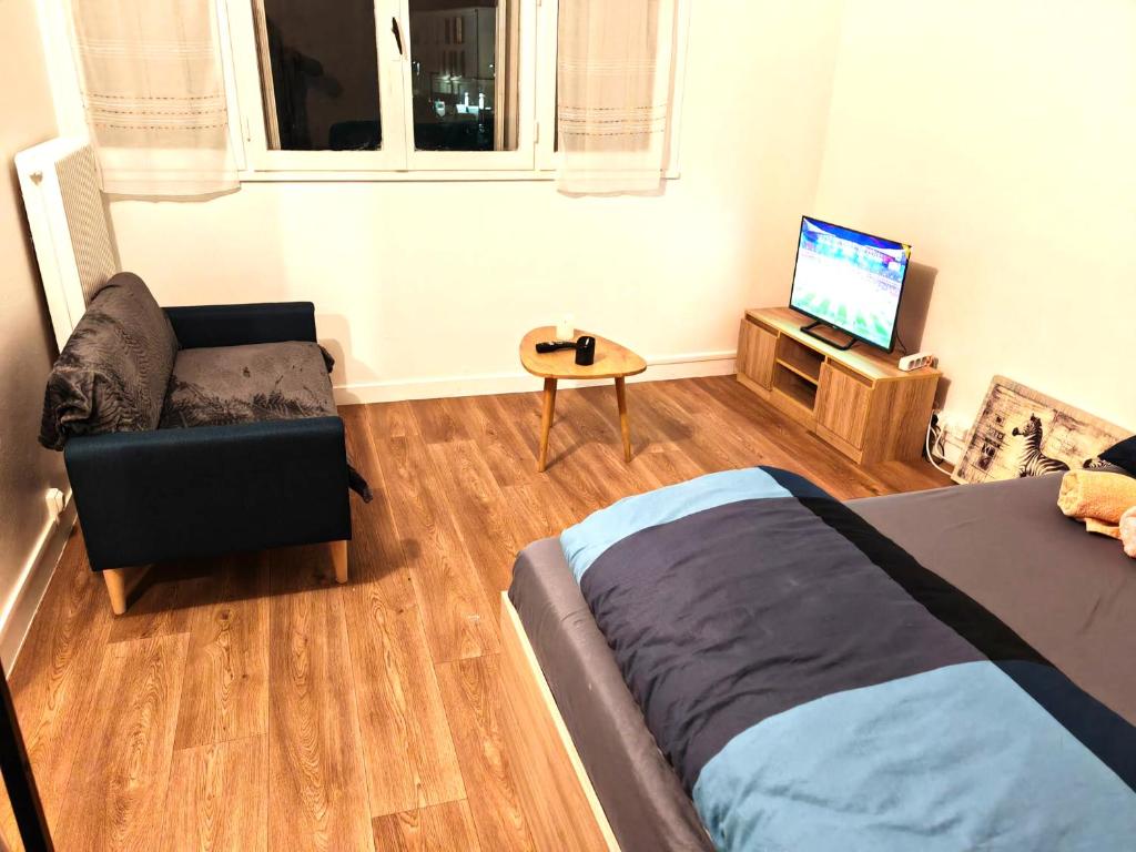 een slaapkamer met een bed, een stoel en een televisie bij F1 équipé avec ascenseur, parking et près des transports in Argenteuil