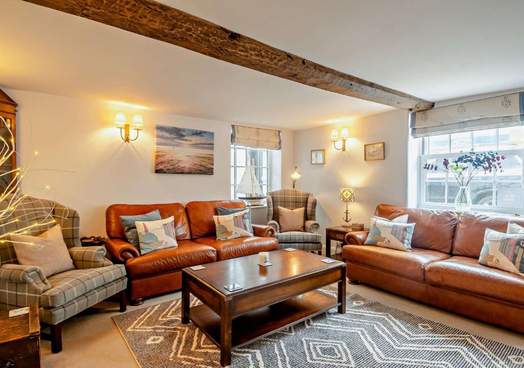 sala de estar con muebles de cuero y mesa en Orford Cottage en Aldeburgh