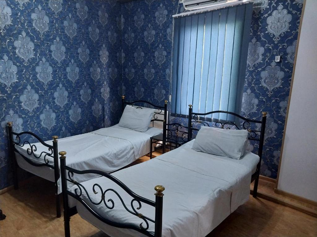 two beds in a room with blue wallpaper at Magnolia in Kutaisi