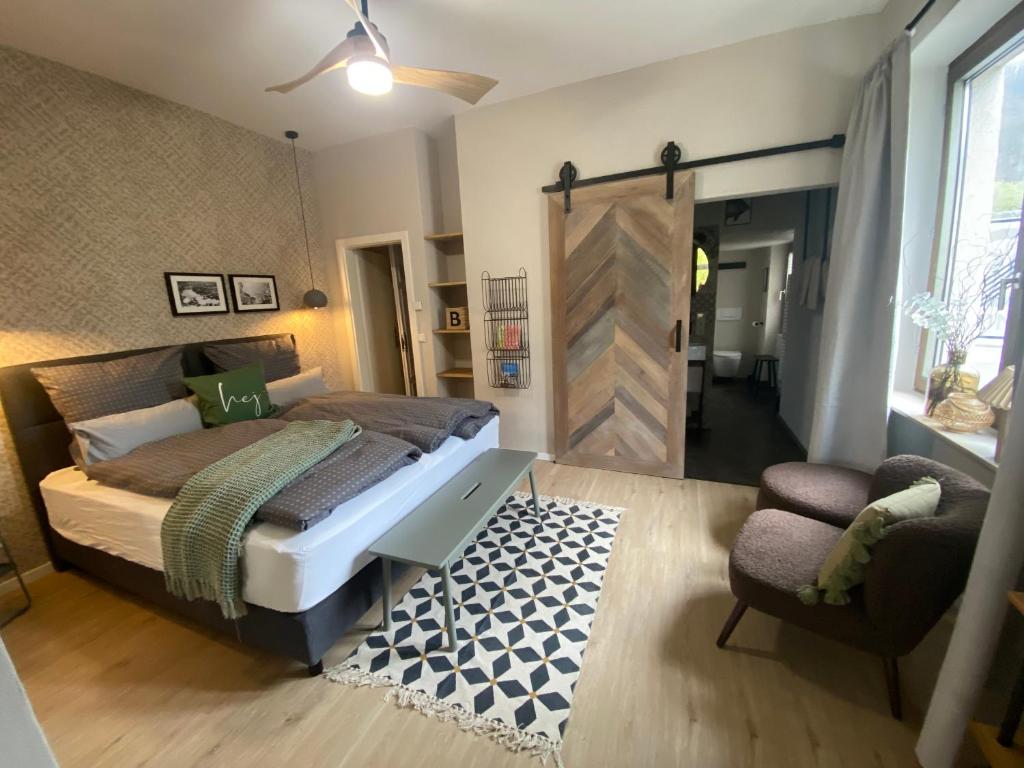een slaapkamer met een bed, een stoel en een deur bij Cues11 in Bernkastel-Kues