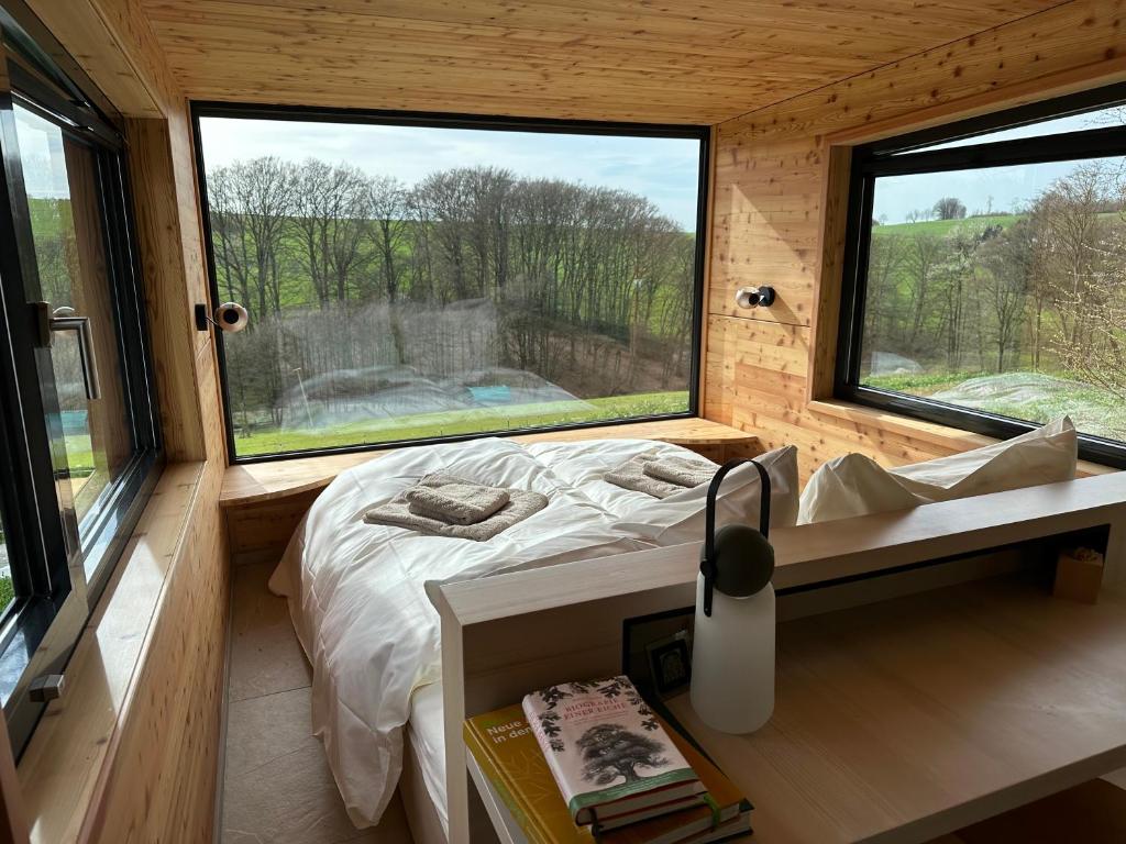a small bedroom with a bed and two windows at K1 Baumhaus in Odenthal
