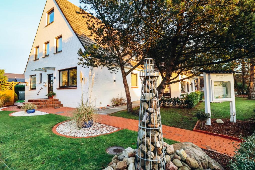 a house with a totem pole in the yard at Hotel Das kleine Glück - Adults Only in Sankt Peter-Ording