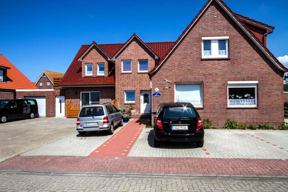 two cars parked in a parking lot in front of a house at Pension Haus My in Norddeich