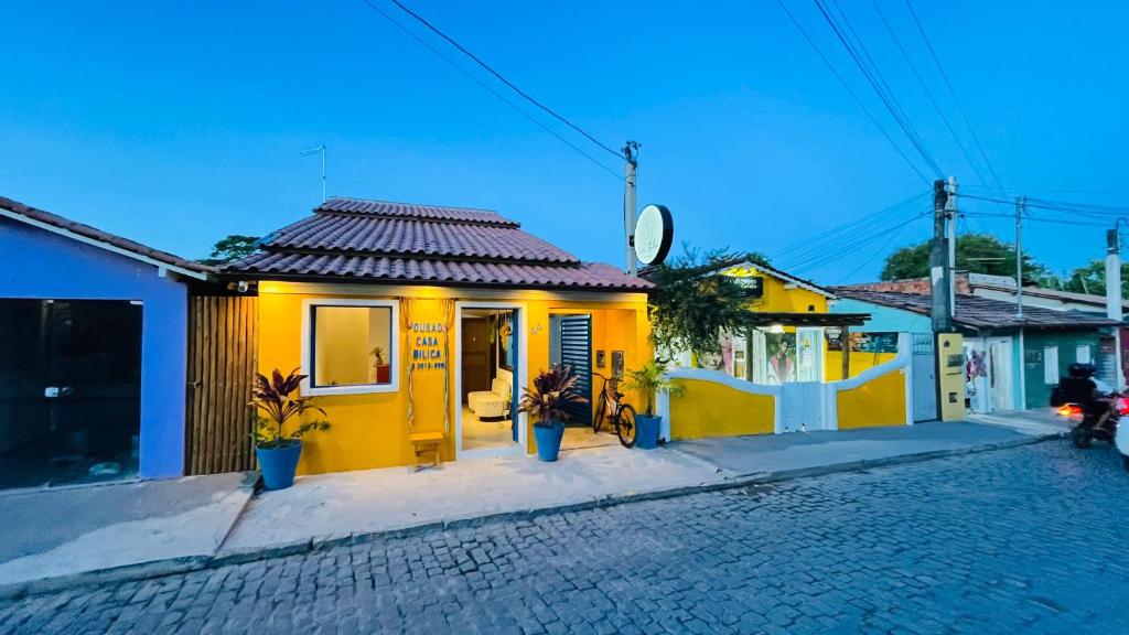 a yellow house with a clock on a street at Pousada Bilica in Arraial d'Ajuda
