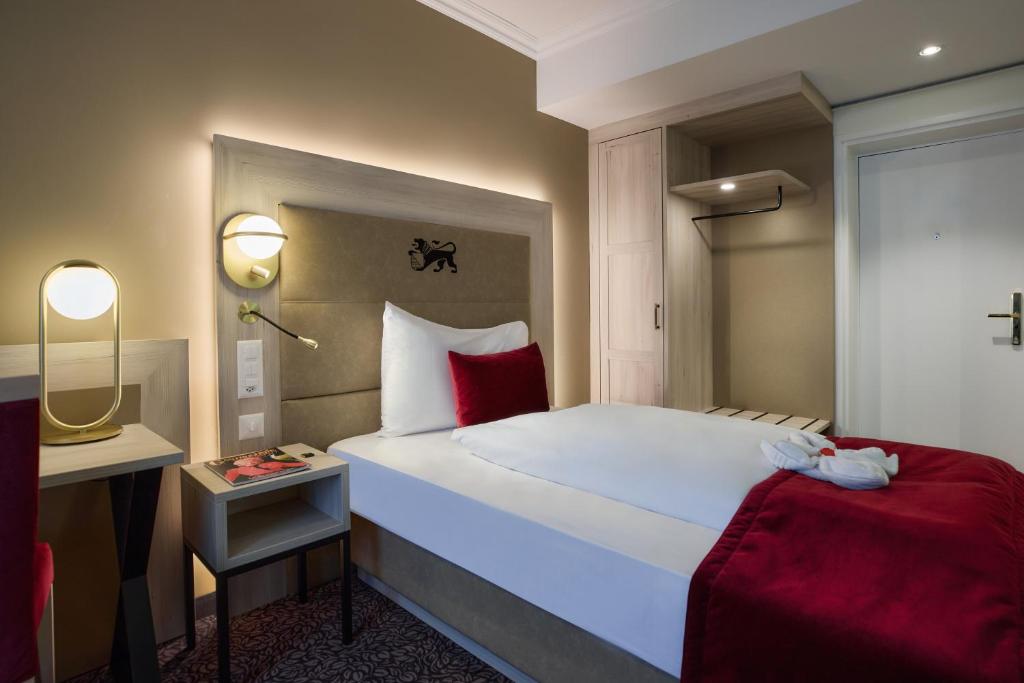a bedroom with a large white bed with red pillows at Hotel St.Gotthard in Zürich