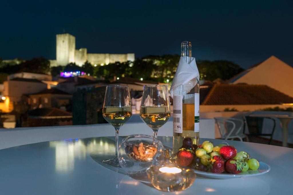 Porta da Arrábida Suites في بالميلا: طاولة مع كأسين من النبيذ وصحن من الفاكهة