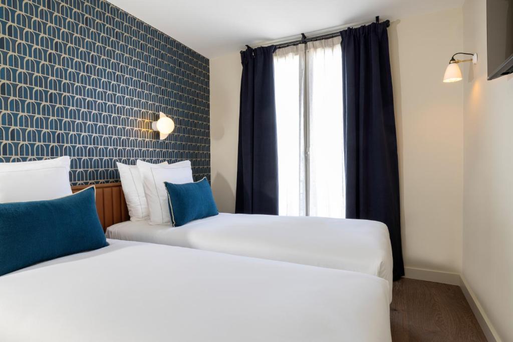 two beds in a room with a window at Bijou Hôtel Paris Boulogne in Boulogne-Billancourt