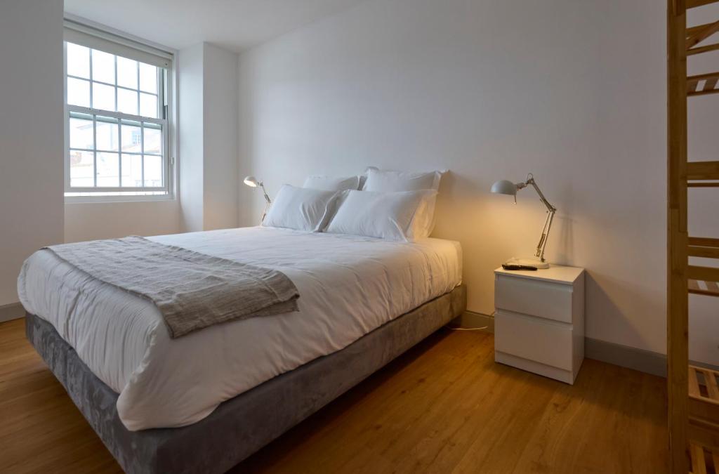 um quarto com uma cama, uma mesa de cabeceira e uma janela em Matriz 55, Hostel & Suites em Ponta Delgada