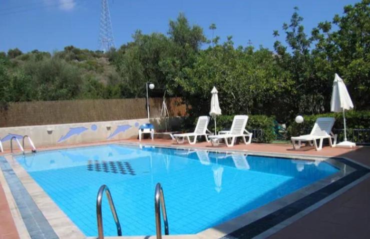une grande piscine avec des chaises et des parasols dans l'établissement 4 Beds Flat with Shared Pool, à Stalida