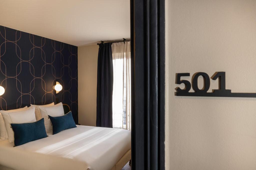 a bedroom with a large bed with blue pillows at Bijou Hôtel Paris Boulogne in Boulogne-Billancourt