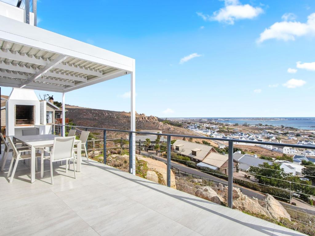 Un patio con una mesa y sillas en un balcón. en Blueberry Villa by Host Agents, en St Helena Bay