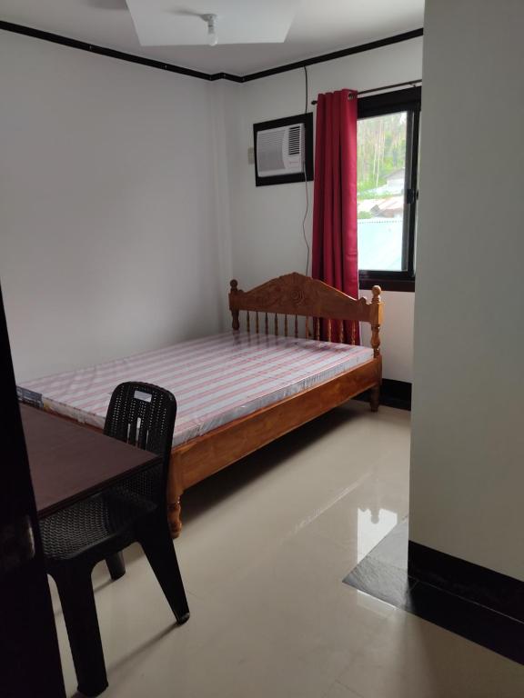 a bedroom with a bed and a table and a window at D & G Transient House in Pintuyan