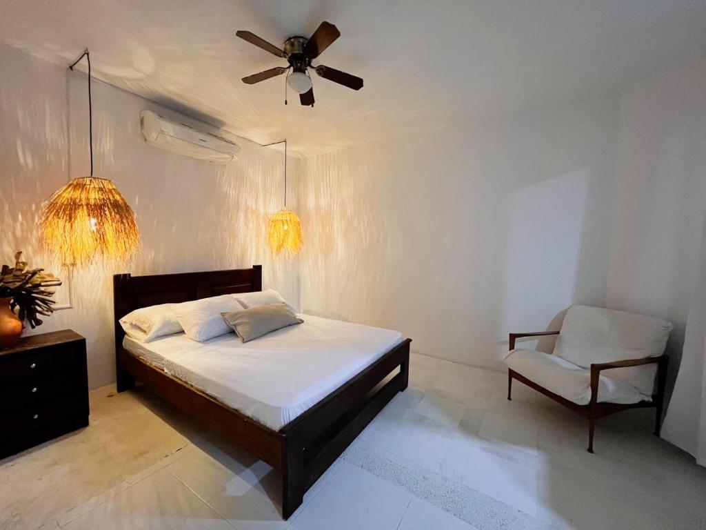 1 dormitorio con 1 cama con ventilador de techo y silla en Hermosa habitación en casa campestre con piscina cerca al aeropuerto en Santa Marta