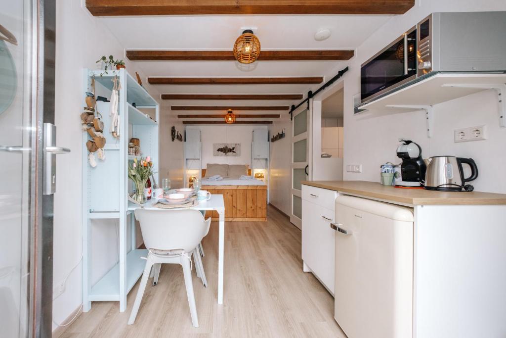 a kitchen with white cabinets and a small table at De Jutter - Zandvoort in Zandvoort