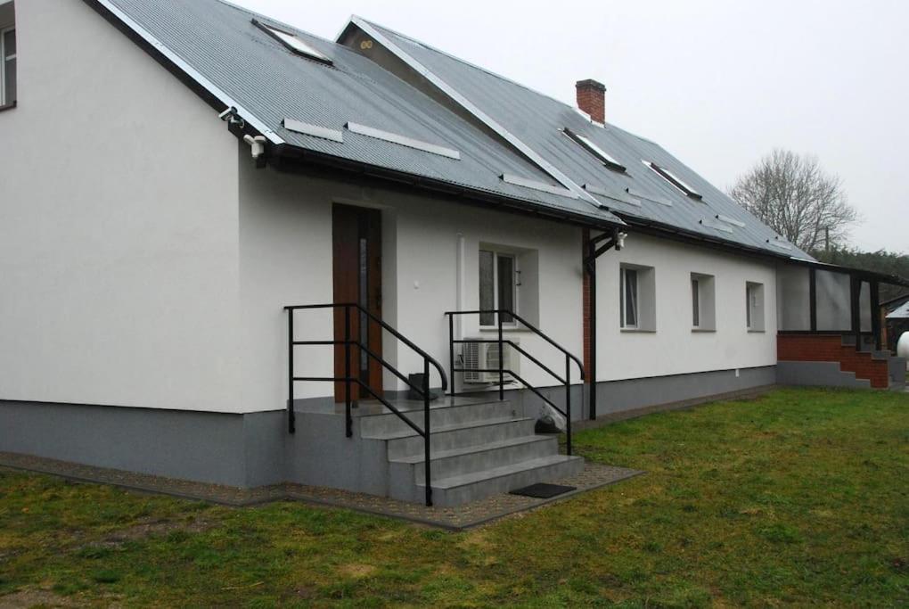 uma casa branca com painéis solares no telhado em Ferienhaushälfte in den Masuren am Fluss nahe dem See em Stacze