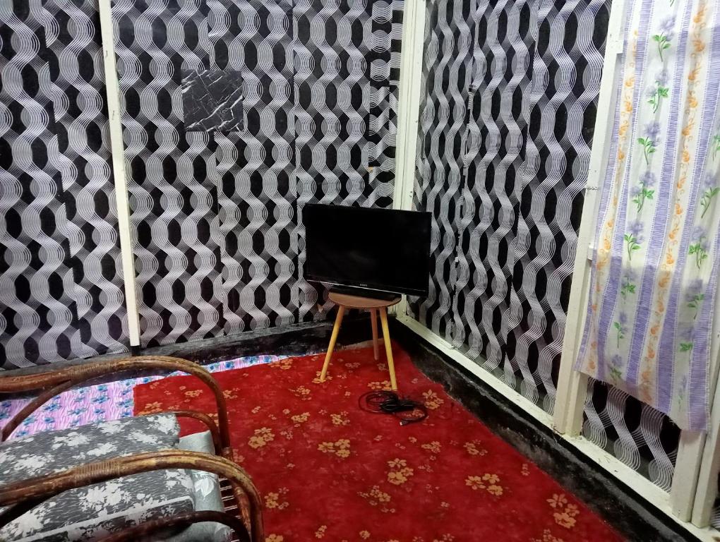 丹那拉打的住宿－BUDJET HOMESTAY CAMERON HIGHLANDS，一间带椅子和桌子上的电视的房间