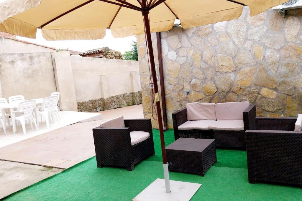 a patio with an umbrella and chairs and a table at Casa Gabritana in Sotillo de las Palomas