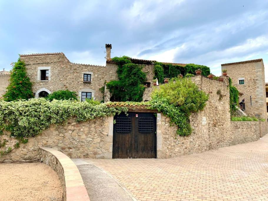 un edificio de piedra con una puerta con hiedra. en Els Racons del Fort Castle hosting up to 18 people, en Capmany