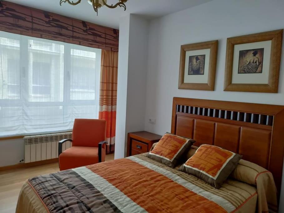 a bedroom with a bed and a chair and a window at Precioso piso proximo a Riazor in A Coruña