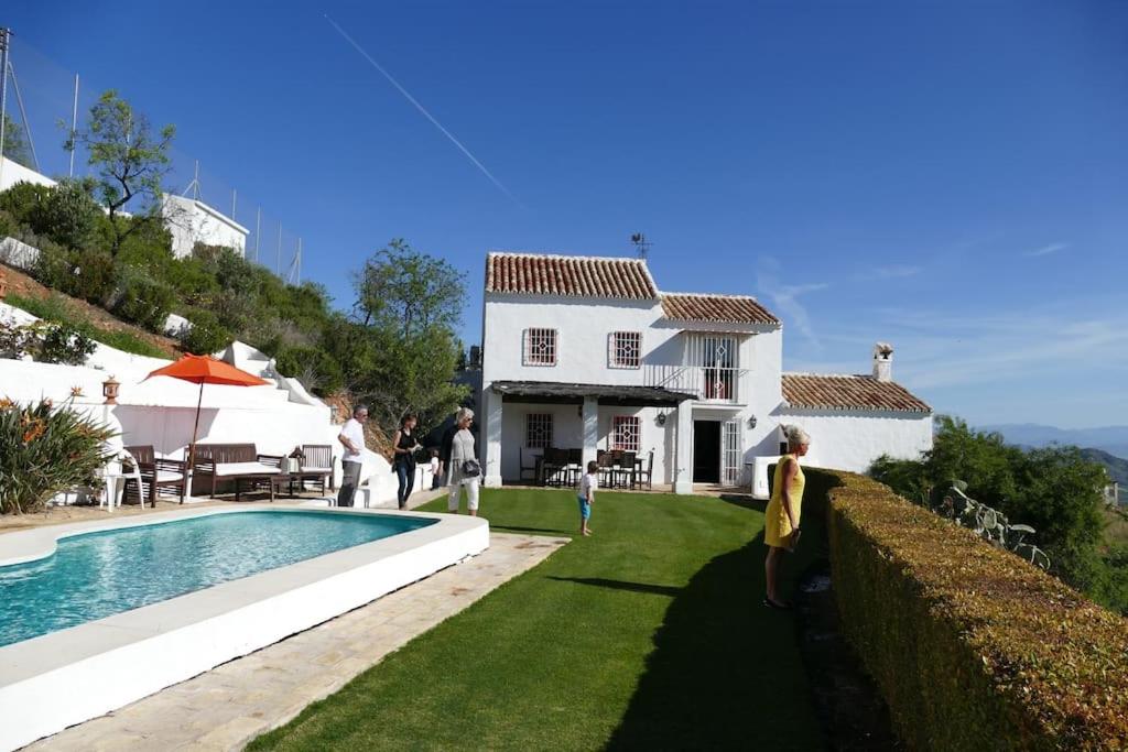 Eine Frau steht vor einem Haus mit Pool in der Unterkunft Charming Spanish Finca in beautiful nature in Málaga