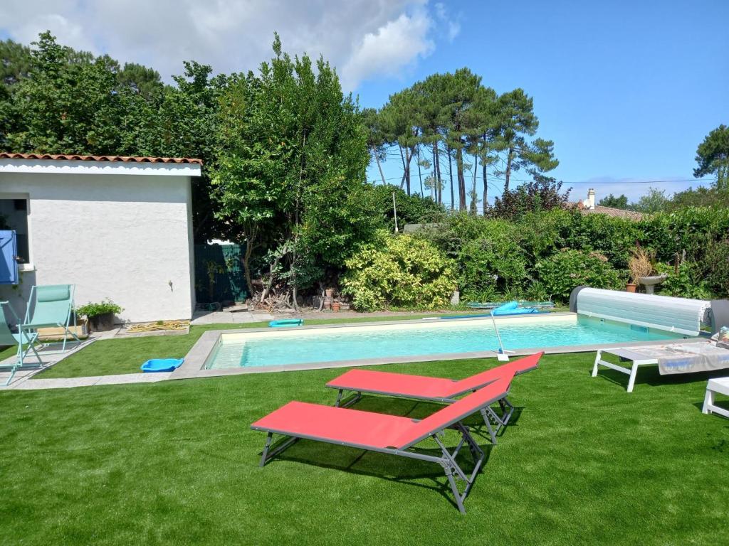 - une piscine avec 2 chaises longues et un sidx rouge dans l'établissement Pause nature au Teich avec piscine, au Teich