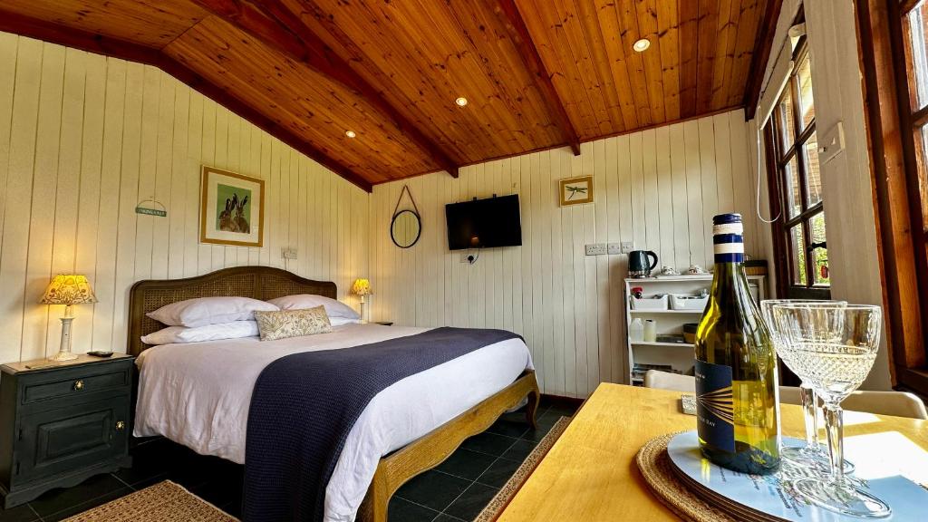Un dormitorio con una cama y una mesa con una botella de vino en The Cider Shed Bed and Breakfast, en Wareham