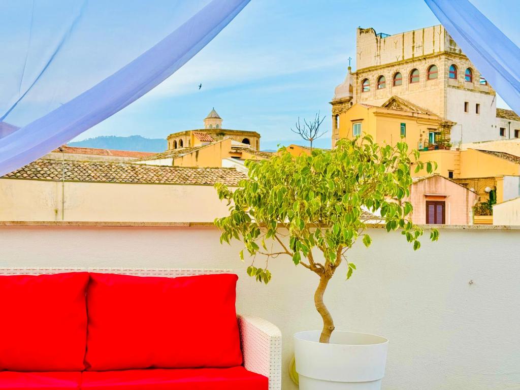 eine rote Couch auf einem Balkon mit einem Baum in der Unterkunft Meetup on The Terrace View With private parking in Palermo