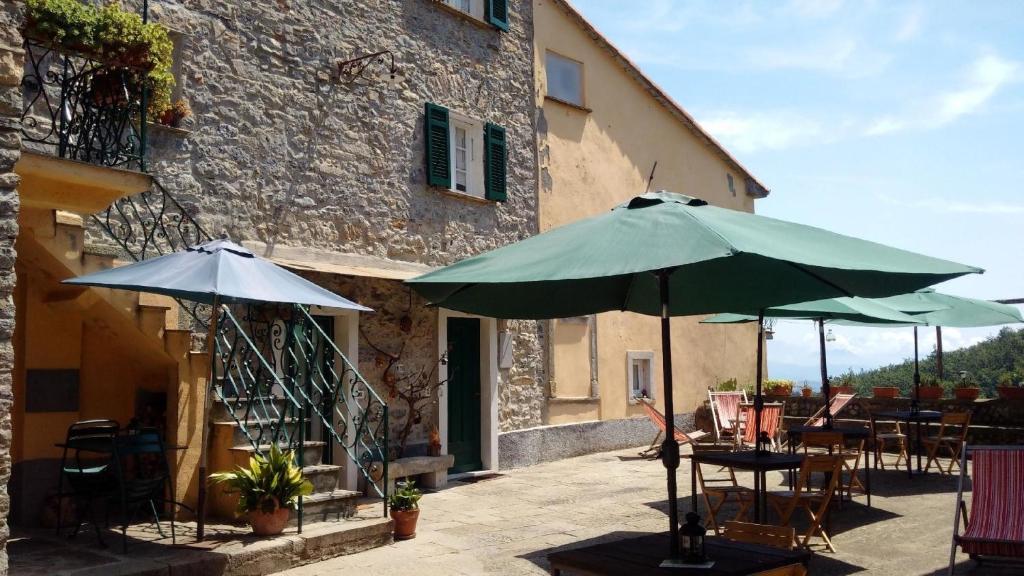 eine Terrasse mit Tischen und Sonnenschirmen vor einem Gebäude in der Unterkunft Ferienwohnung für 2 Personen  2 Kinder ca 35 m in Castè, Italienische Riviera Golf von La Spezia in Quaratica