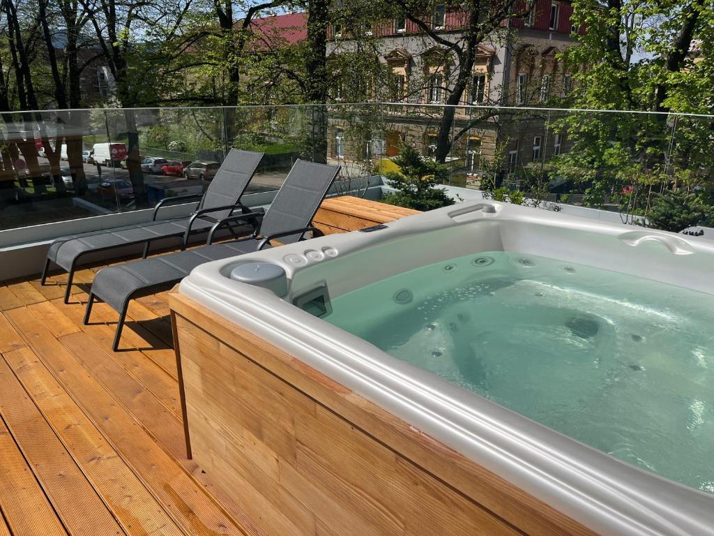 bañera de hidromasaje en una terraza de madera con sillas en Apartmány Vila Terasy en Liberec