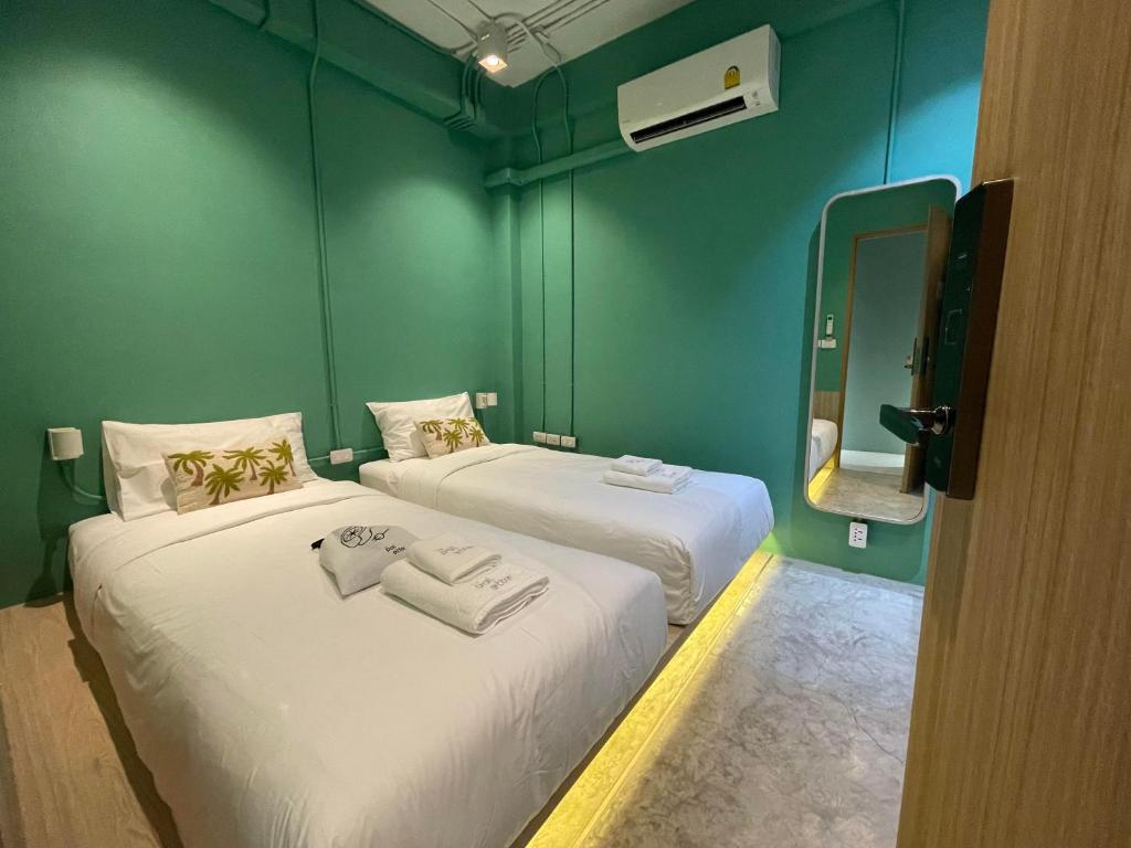 2 camas en una habitación pequeña con paredes verdes en The Palette Bangkok Hotel en Bangkok
