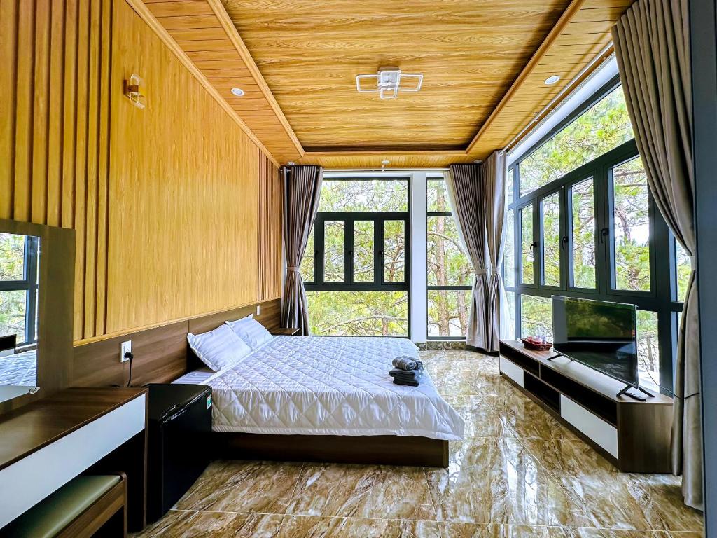 um quarto com uma cama num quarto com janelas em HeniSi Hotel Măng Đen (HeniSi 2) em Kon Von Kla