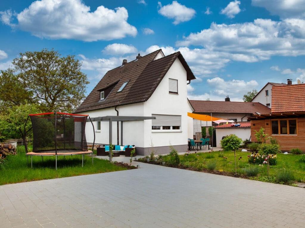 ein weißes Haus mit einem Spielplatz im Hof in der Unterkunft Sun Garden Modern retreat in Allersberg