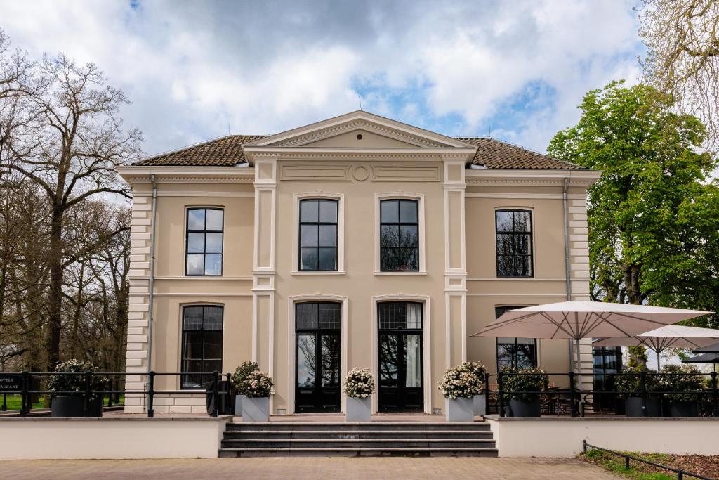 a large tan house with black windows and an umbrella at Pillows Luxury Boutique Hotel aan de IJssel in Deventer