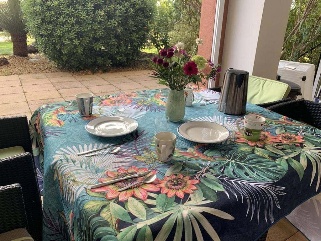 une table avec des assiettes et un vase avec des fleurs. dans l'établissement Appartement Hyères, 2 pièces, 4 personnes - FR-1-335-194, à Hyères