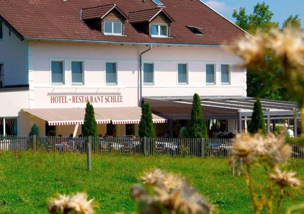 ein großes weißes Gebäude mit einem Zaun davor in der Unterkunft Hotel Schlee in Hohenschäftlarn