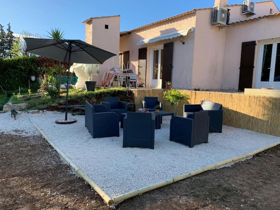 une terrasse avec des chaises bleues et un parasol dans l'établissement Magnifique villa - 9 personnes - Proche de la mer, à Saint-Brès