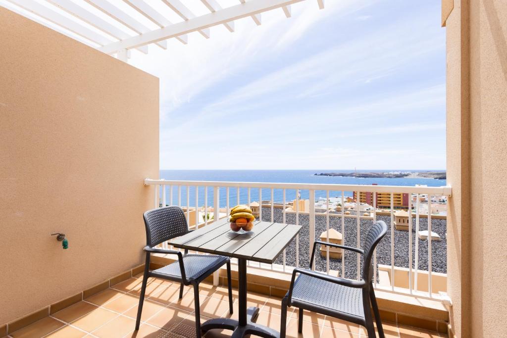 einen Balkon mit einem Tisch, Stühlen und Meerblick in der Unterkunft Home2Book Amazing Sea Views & Terrace, El Porís in Poris de Abona