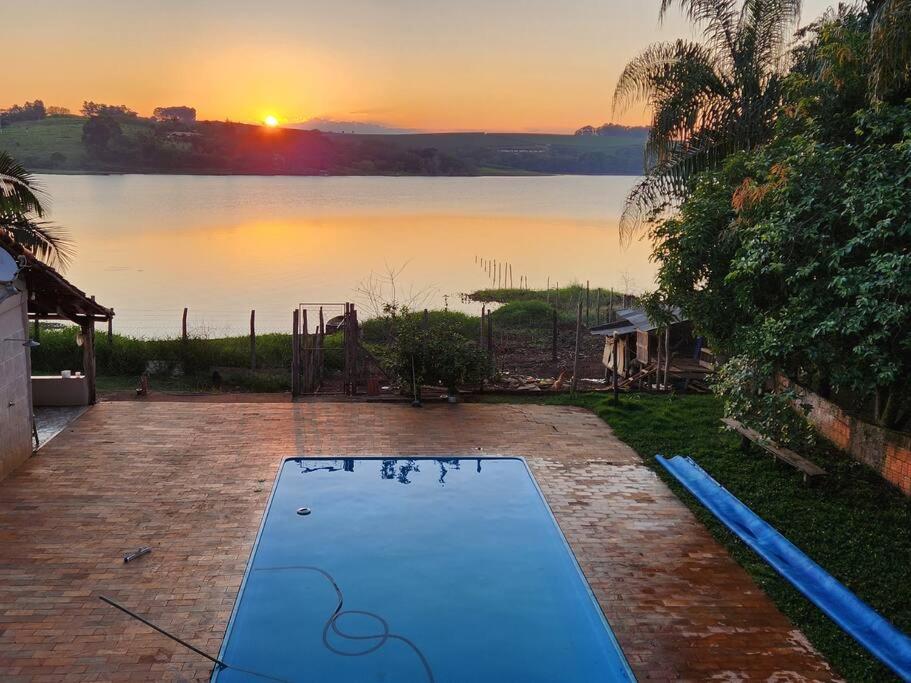 an empty swimming pool with the sunset in the background at Casa Alfenas Represa Furnas c/ Piscina Aquecida 12 pessoas in Alfenas