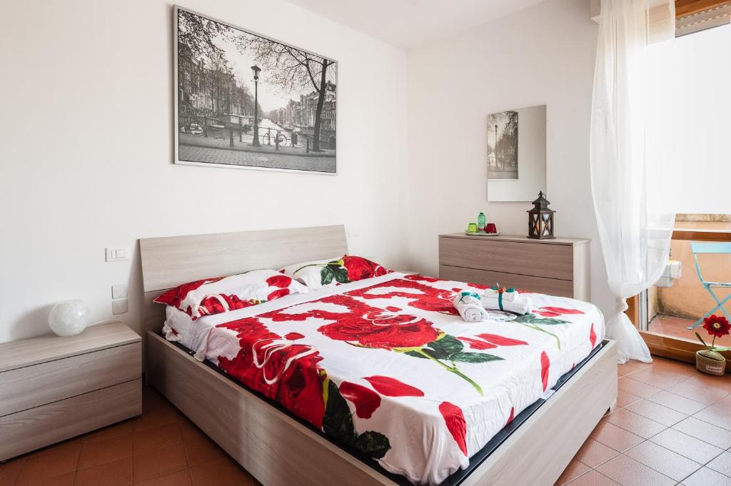 Benvenuti a casa في بيزا: غرفة نوم بسرير وبطانية حمراء وبيضاء