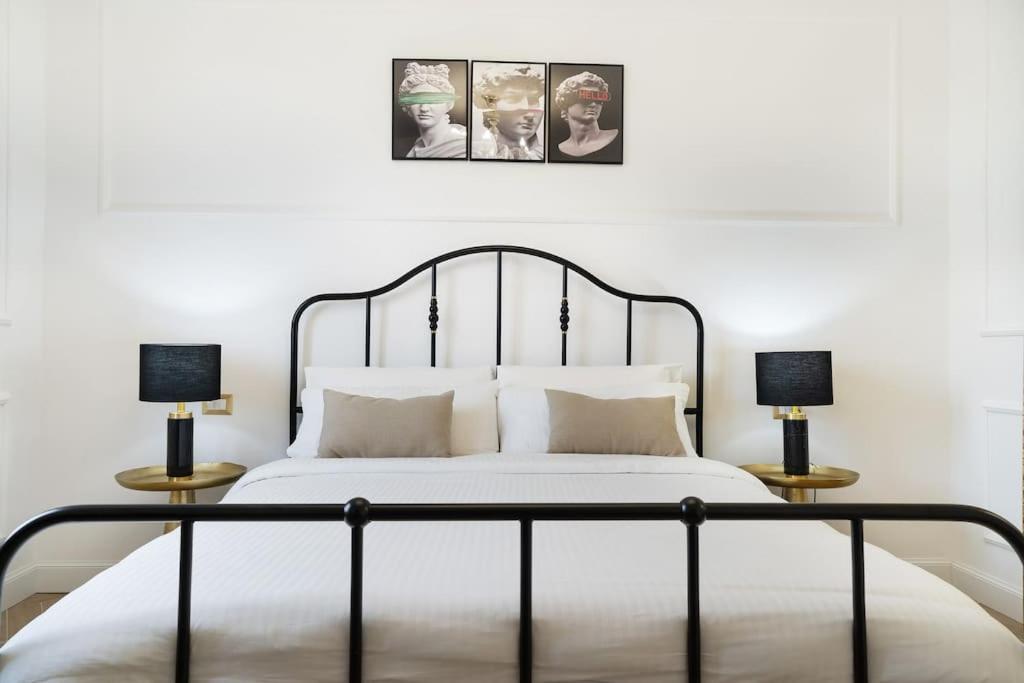 a bedroom with a white bed with two lamps at In Villa Apartment in Rome