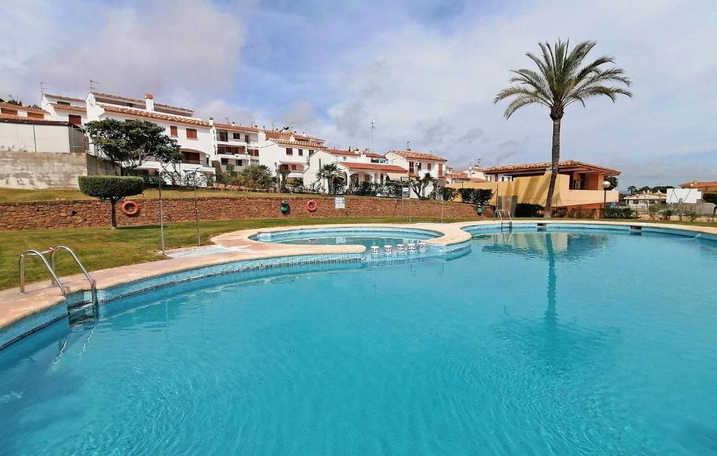 a large swimming pool with a palm tree and buildings at 3 Bedroom Cozy Home In Peñíscola in Peñíscola
