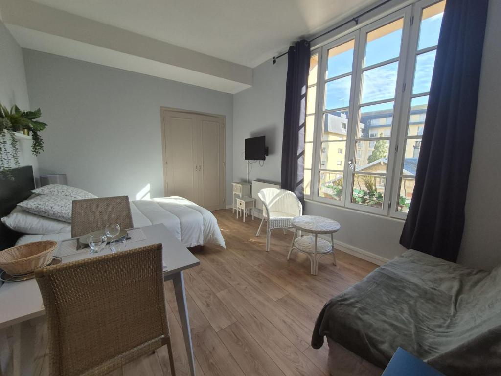 Habitación de hotel con cama, mesa y sillas en Studio proche lac en Bagnoles de l'Orne