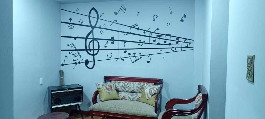 リオバンバにあるSuite Privada Riobambaの椅子と音楽音符が壁に付いた客室です。